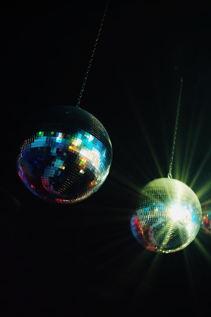 Two shining disco balls with colorful light reflections create a lively party atmosphere.