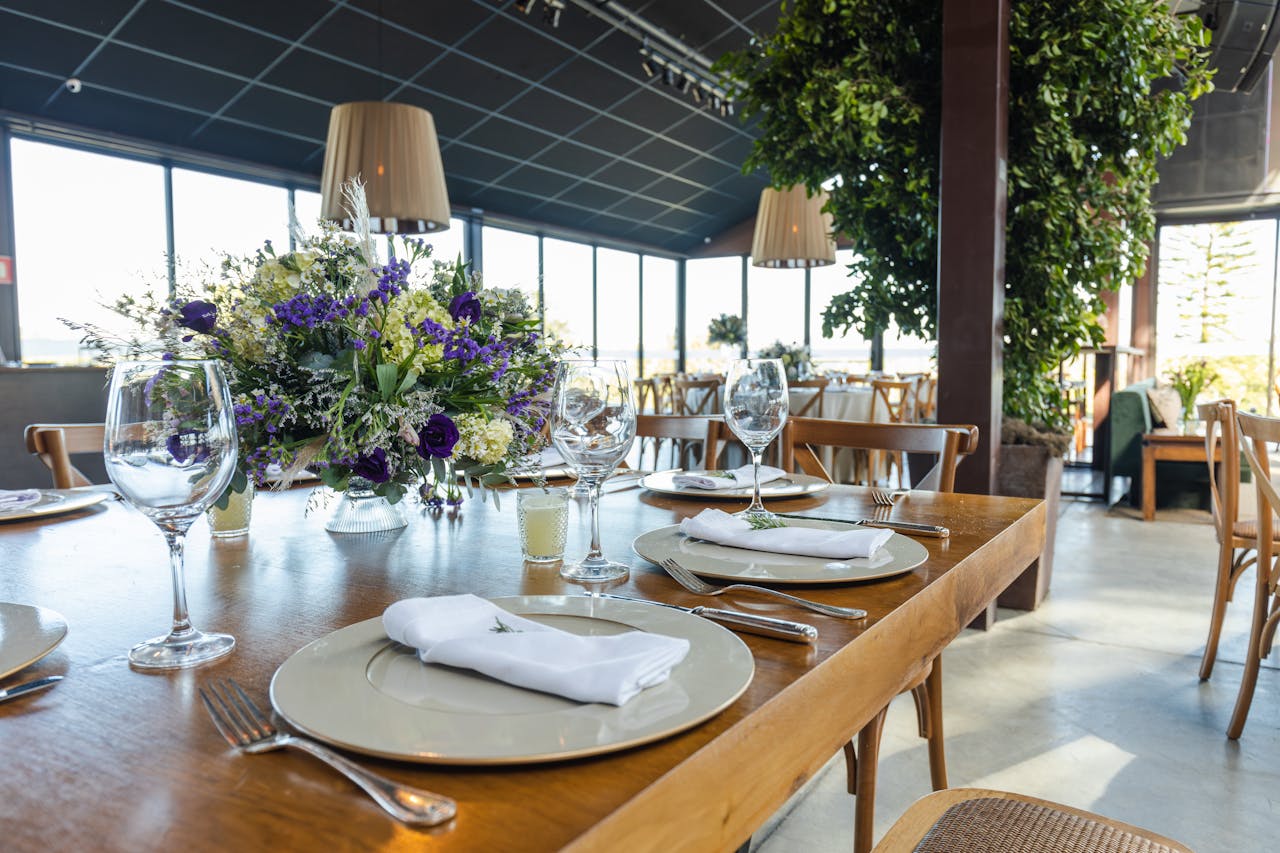 A beautifully arranged wedding table setting in a well-lit reception hall with floral centerpieces.