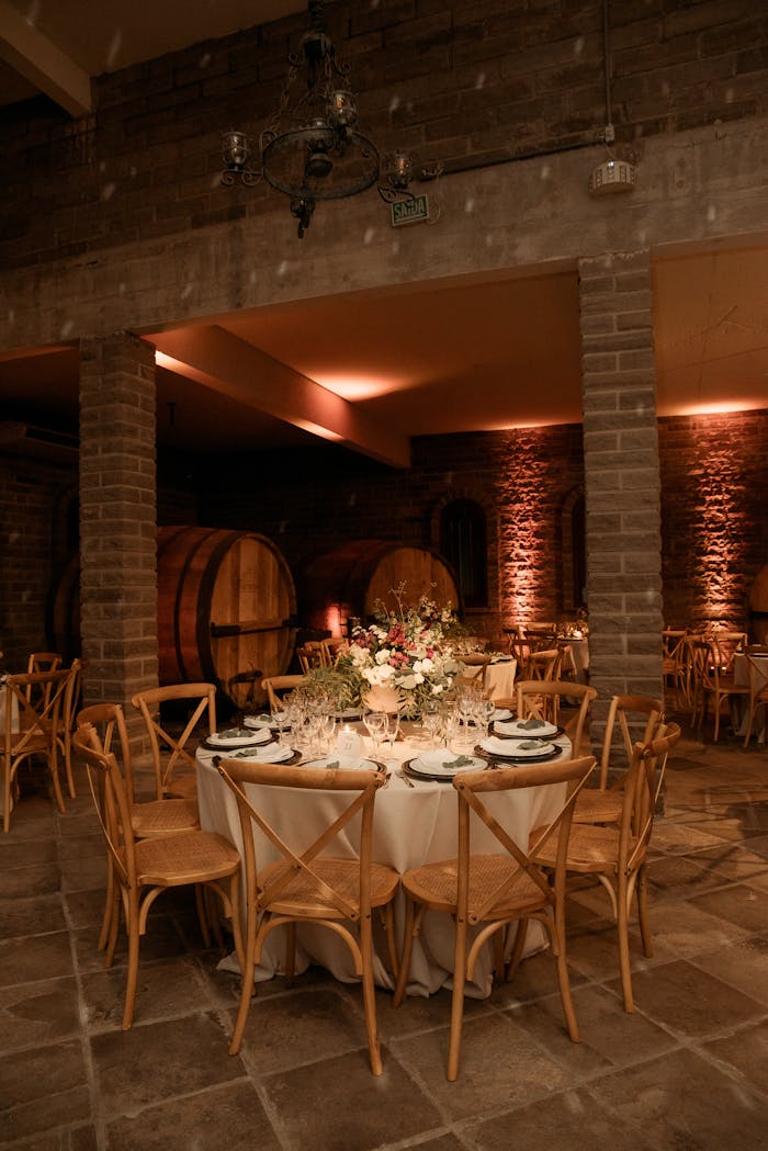 Beautifully decorated table setting in a cozy wine cellar with wooden chairs and ambient lighting.