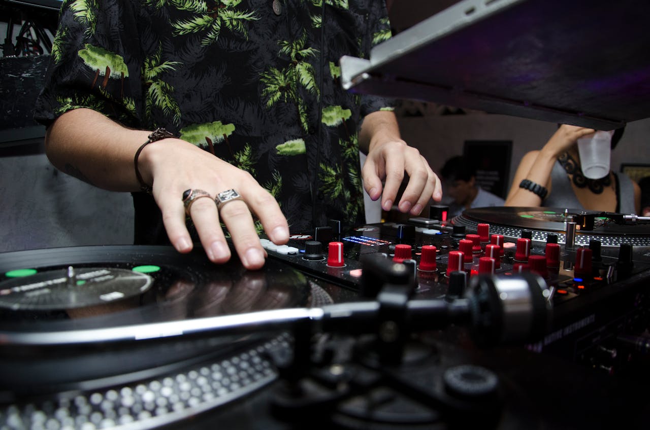 Close-up of a DJ mixing music at a club with vibrant atmosphere and crowd.